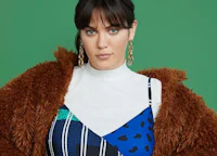 a woman in a blue and white dress with a brown fur coat